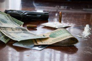 table with drugs, money, and a pistol on top