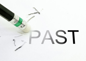 Pencil with eraser erasing parts of the word PAST, which is written in all capital letters in dark font
